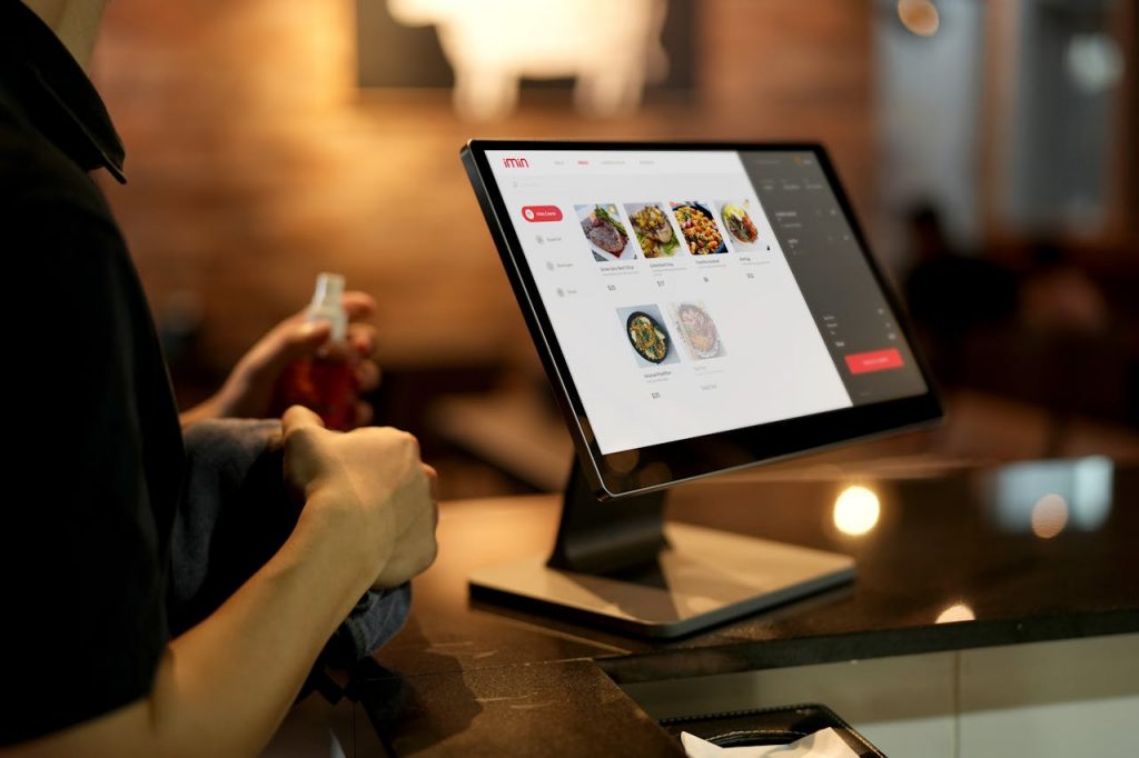 pexels-photo-12935078 A person using a touchscreen ordering system in a modern restaurant setting.